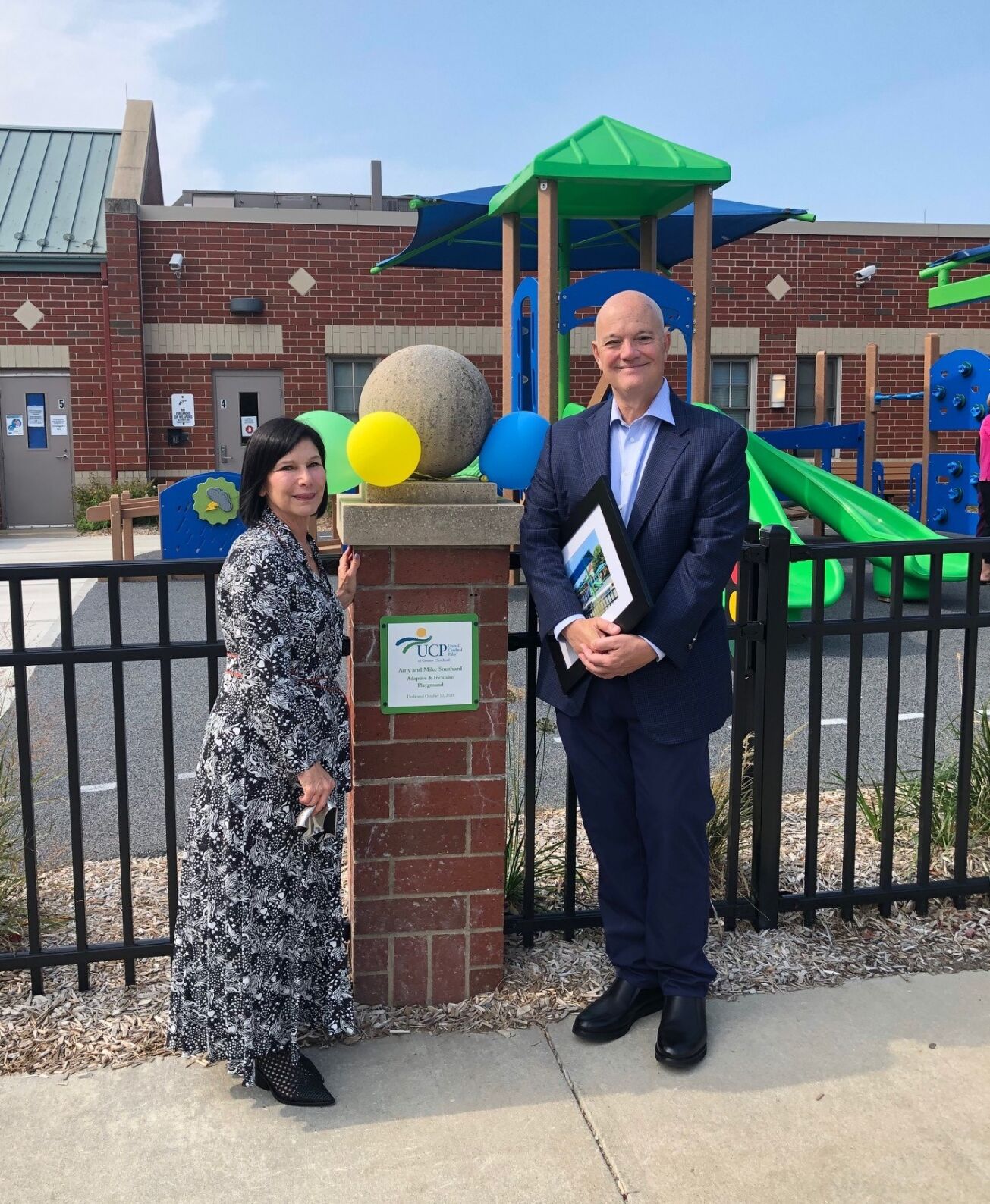 Amy and Mike Southard stand outside the new playground with the naming plate.jpg